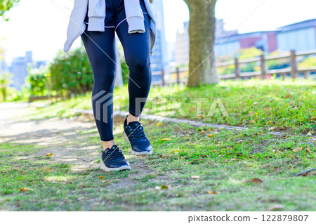 A cool woman jogging on a road with sunlight filtering through the trees Walking Diet Exercise Exercise Trimming 122879807