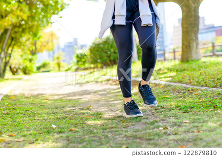A cool woman jogging on a road with sunlight filtering through the trees Walking Diet Exercise Exercise Trimming 122879810