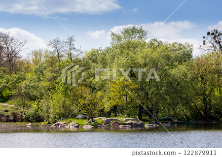 green coast of a beautiful small river with white clouds in reflection green coast of a beautiful small river with white clouds in reflection 122879911
