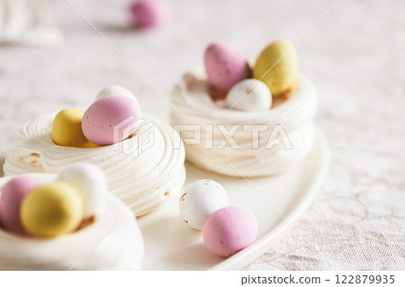 Easter meringue nests with colorful sweet eggs on plate. Easter dessert closeup. 122879935