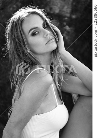 Serene Black and White Portrait of a Woman in a White Top with Sunlit Hair in Nature 122880660