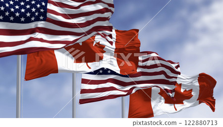 Canada and american national flags waving in the wind on a clear day Canada and american national flags waving in the wind on a clear day 122880713