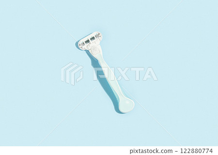 Minimalist elegance: Razor in sharp relief against a bold blue canvas with dramatic shadows 122880774