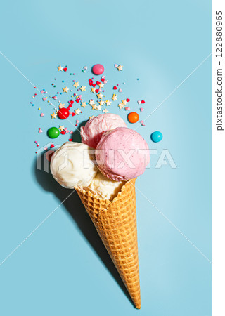 Waffle cone with vanilla and strawberry ice cream scoops 122880965