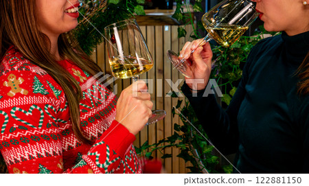 Christmas Cheers: Two Friends Toasting with White Wine in a Festive Setting 122881150