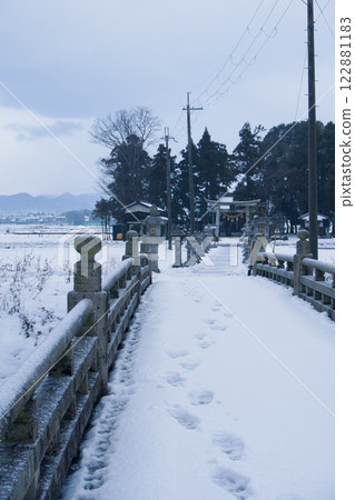 A sacred forest on the other side of a snow-covered bridge 122881183