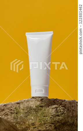 White plastic tube stands on a stone on a yellow background. Container for cosmetics and toothpaste White plastic tube stands on a stone on a yellow background. Container for cosmetics and toothpaste 122881462