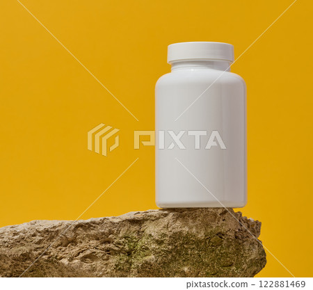 White plastic medicine jar on stone, yellow background. Mock up White plastic medicine jar on stone, yellow background. Mock up 122881469