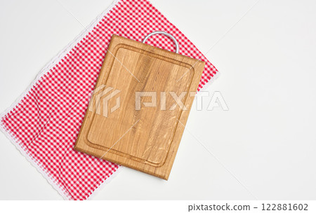 Empty wooden cutting board and red towel on white background. Copy space 122881602