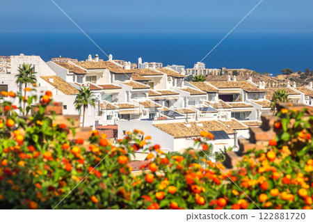 Mediterranean coastal town view with white houses and orange flowers. 122881720