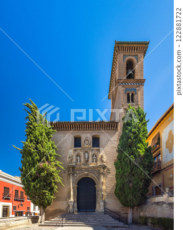 Church of Saint Anne at Plaza Nueva square in Granada town in Spain. Historic church facade with bell tower, under a vibrant blue sky. Architectural detail and landscaping enhance the scene. 122881722