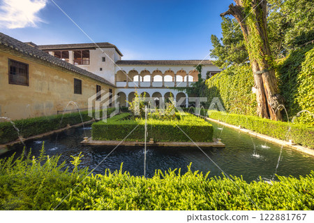 The Generalife Palace at the Alhambra complex in Granada town, Andalusia, Spain. Serene courtyard with fountains and lush greenery, featuring a classic architectural design. 122881767