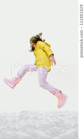 Young girl wearing colorful wear, jumping on snow, looking excited, moving forward with energetic pose against white background. 122881829