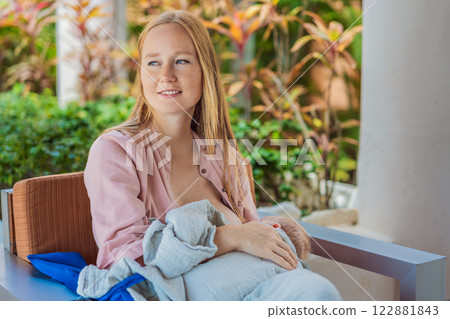A mother breastfeeds her baby in a cozy cafe, embracing a natural and nurturing moment amidst a casual, public setting. This intimate scene reflects modern parenting, maternal love, and the beauty of 122881843