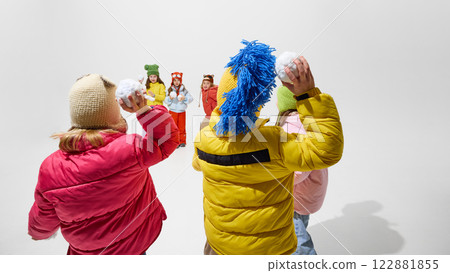 Group of children, holding snowballs, preparing for playful snowball fight, wearing colorful winter clothes, enjoying fun winter activity against white studio background. Group of children, holding snowballs, preparing for playful snowball fight, wearing colorful winter clothes, enjoying fun winter activity against white studio background. 122881855
