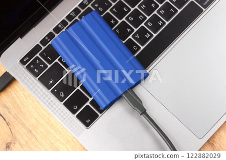 External hard drive on laptop keyboard, office desk setup. 122882029