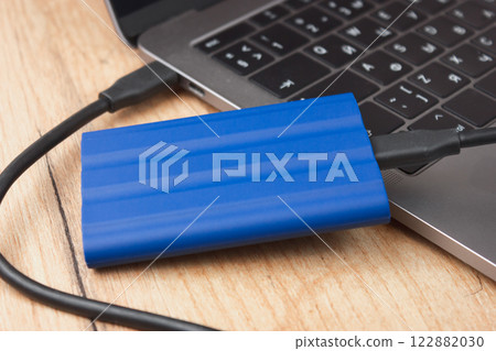External hard drive connected to a laptop on a wooden desk. 122882030