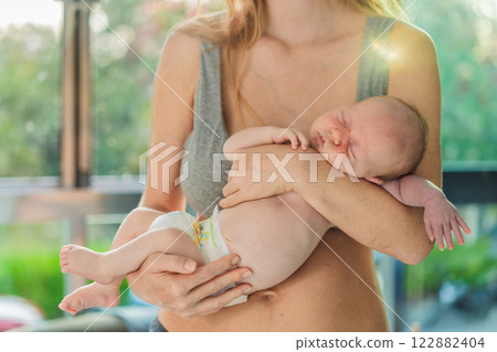 A mother lovingly embraces her newborn baby, holding them close to her chest. A tender moment of warmth, security, and deep maternal love, symbolizing bonding, comfort, and the unbreakable connection 122882404