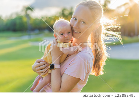 Young mother enjoying a peaceful walk in the park with her one-month-old baby. Motherhood, bonding, and outdoor family time concept 122882493
