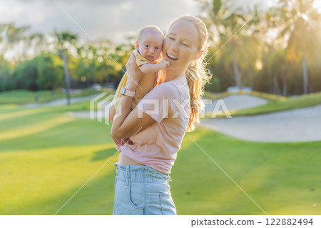 Young mother enjoying a peaceful walk in the park with her one-month-old baby. Motherhood, bonding, and outdoor family time concept Young mother enjoying a peaceful walk in the park with her one-month-old baby. Motherhood, bonding, and outdoor family time concept 122882494