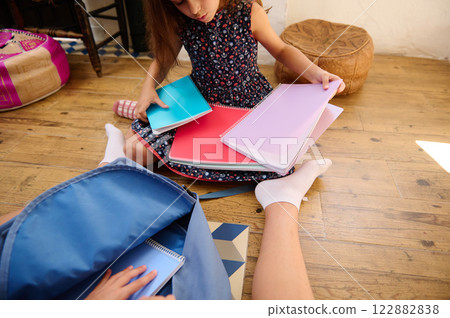 Child Sorting Notebooks on Floor 122882838