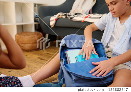 Boy packing backpack with notebooks Boy packing backpack with notebooks 122882847