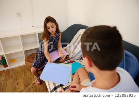 Children Sharing Notebooks on a Sofa Children Sharing Notebooks on a Sofa 122882926