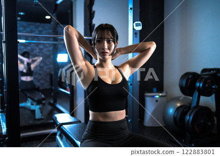 Cool woman tying her hair while working out at the gym Power rack Bench press Muscle training girl Cool woman tying her hair while working out at the gym Power rack Bench press Muscle training girl 122883801