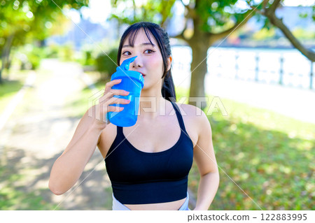 一位酷酷的女人在陽光下沿著小路散步補充水分 蛋白質鍛煉鍛煉 一位酷酷的女人在陽光下沿著小路散步補充水分 蛋白質鍛煉鍛煉 122883995
