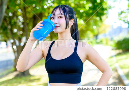 A cool woman hydrating while walking along a path in the sunlight Protein Exercise Exercise Trimming A cool woman hydrating while walking along a path in the sunlight Protein Exercise Exercise Trimming 122883998