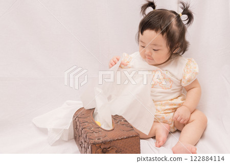 [Baby with twin tails playing with tissues] 122884114