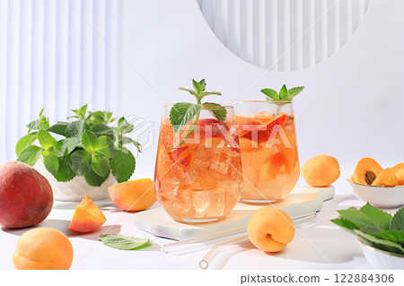 Ice peach tea or cocktail with mint and apricots, a recipe for a refreshing summer drink. Two glasses with peach fruit lemonade on a light table, detox diet and weight loss concept, menu for Ice peach tea or cocktail with mint and apricots, a recipe for a refreshing summer drink. Two glasses with peach fruit lemonade on a light table, detox diet and weight loss concept, menu for 122884306