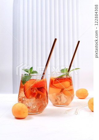 Ice peach tea or cocktail with mint and apricots, a recipe for a refreshing summer drink. Two glasses with peach fruit lemonade on a light table, detox diet and weight loss concept, menu for Ice peach tea or cocktail with mint and apricots, a recipe for a refreshing summer drink. Two glasses with peach fruit lemonade on a light table, detox diet and weight loss concept, menu for 122884308
