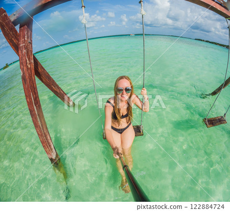 Woman standing in the crystal-clear waters of Lake Bacalar, Mexico, enjoying the serene beauty of the landscape. Tranquil moment in nature, outdoor escape, and relaxation concept Woman standing in the crystal-clear waters of Lake Bacalar, Mexico, enjoying the serene beauty of the landscape. Tranquil moment in nature, outdoor escape, and relaxation concept 122884724