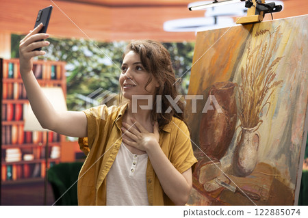 Influencer artist filming her finished rustic artwork for an online branding and self promotion, explaining the painting technique done in art studio. Painter advertising her artistic progress. Influencer artist filming her finished rustic artwork for an online branding and self promotion, explaining the painting technique done in art studio. Painter advertising her artistic progress. 122885074