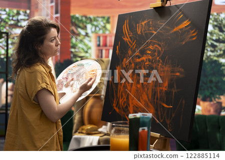 In an art studio, painter uses watercolor paint to create a finger painted masterpiece. Creative talented artist showing her inspiration to create a rustic colorful artwork with handprints. In an art studio, painter uses watercolor paint to create a finger painted masterpiece. Creative talented artist showing her inspiration to create a rustic colorful artwork with handprints. 122885114