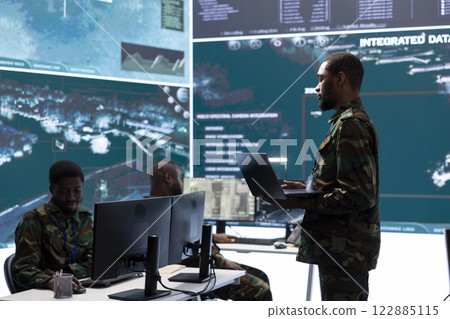 Military specialists monitor satellite radar real time information, intelligence for field missions. Soldiers work on decision making to help the troops, surveillance cctv systems in control center. Military specialists monitor satellite radar real time information, intelligence for field missions. Soldiers work on decision making to help the troops, surveillance cctv systems in control center. 122885115