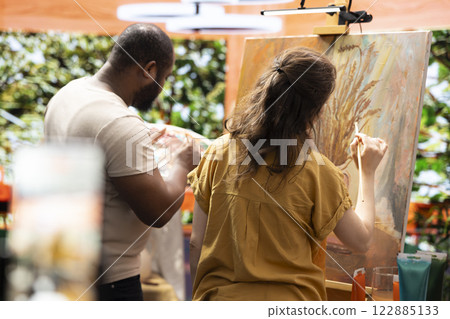 Team of painters recording an artistic tutorial for the internet art class, teaching painting techniques and showing demonstration for creativity. Man and woman working on e learning lesson. 122885133
