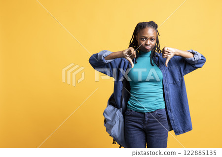 Upset woman showing thumbs down sign gesturing, disapproving, offering negative feedback. Disappointed african american girl doing rejection hand gesture, studio background Upset woman showing thumbs down sign gesturing, disapproving, offering negative feedback. Disappointed african american girl doing rejection hand gesture, studio background 122885135
