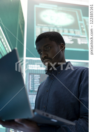 Cyber investigation specialist working in a governmental hacking room, using a laptop and big screen for phishing detection. Examining online security server to prevent digital threats. 122885161