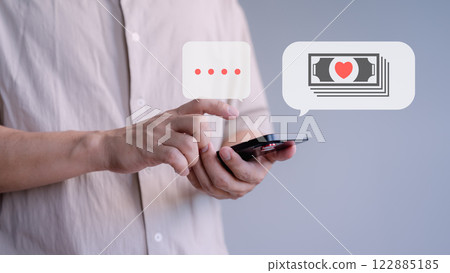 Close-up of a person using a smartphone with speech bubbles for texting and money with a heart symbol, representing online communication and financial transactions, gift for lover in Valentine. 122885185