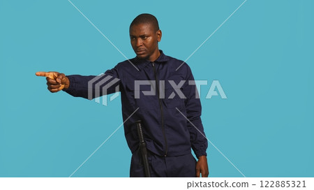 Security guard pointing finger at people to prevent them from gaining access in restricted areas. Portrait of stern bodyguard scolding and telling off unwanted visitors, studio background, camera B Security guard pointing finger at people to prevent them from gaining access in restricted areas. Portrait of stern bodyguard scolding and telling off unwanted visitors, studio background, camera B 122885321