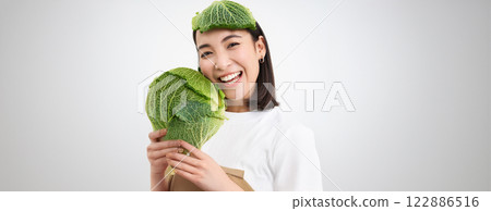 Close up portrait of healthy smiling asian woman, showing cabbage, green letture, with leaf on head, isolated on white background Close up portrait of healthy smiling asian woman, showing cabbage, green letture, with leaf on head, isolated on white background 122886516