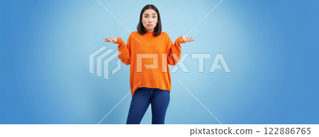 I dont know. Puzzled asian woman shrugs shoulders with hands spread sideways, confused, dont know what to do, clueless and unaware what happened, blue background I dont know. Puzzled asian woman shrugs shoulders with hands spread sideways, confused, dont know what to do, clueless and unaware what happened, blue background 122886765