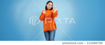 Stop it, no photos please. Upset asian girl blocks camera with hands, doesnt want to take pictures, stands over blue background Stop it, no photos please. Upset asian girl blocks camera with hands, doesnt want to take pictures, stands over blue background 122886789