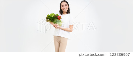 Portrait of smiling healthy woman, vegetarian shows green organic vegetables and looking happy, isolated on white background Portrait of smiling healthy woman, vegetarian shows green organic vegetables and looking happy, isolated on white background 122886907