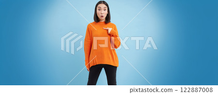 Surprised asian girl points at herself, drops jaw and say wow, impressed, being chosen, picked by someone, stands over blue background Surprised asian girl points at herself, drops jaw and say wow, impressed, being chosen, picked by someone, stands over blue background 122887008