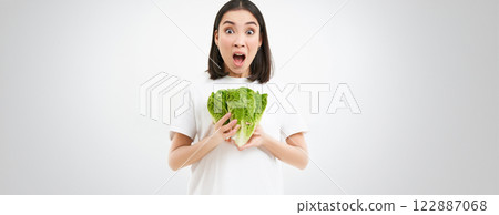 Woman with shocked face, screams, holds vegetable, raw food, eats cabbage on diet, white background 122887068