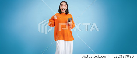 Happy asian woman with smartphone, found great offer online on mobile phone, excited over discounts in app, stands over blue background Happy asian woman with smartphone, found great offer online on mobile phone, excited over discounts in app, stands over blue background 122887080