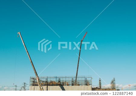 Crane stretching out against the blue sky and scaffolding for building construction Film-like Crane stretching out against the blue sky and scaffolding for building construction Film-like 122887140